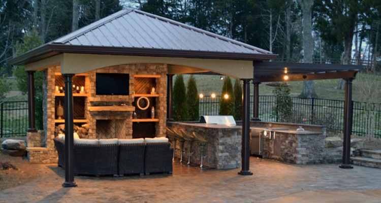 Outdoor pergola with couch, TV, barbecue, and outdoor fountain. 