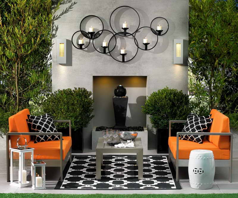 Backyard patio with furniture, decor, and black bubbling fountain. 